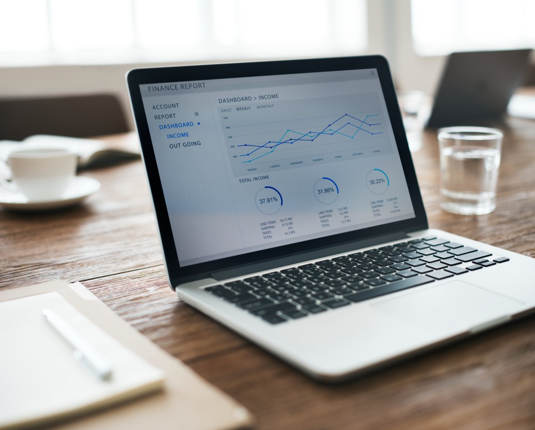 Laptop displaying financial reporting data on a wooden desk
