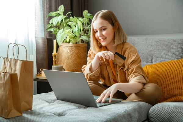 beautiful-young-woman-shopper-makes-online-purchases-using-laptop-credit-debit-cards-while-sitting-couch-home-happy-smiling-woman-buyer-purchases